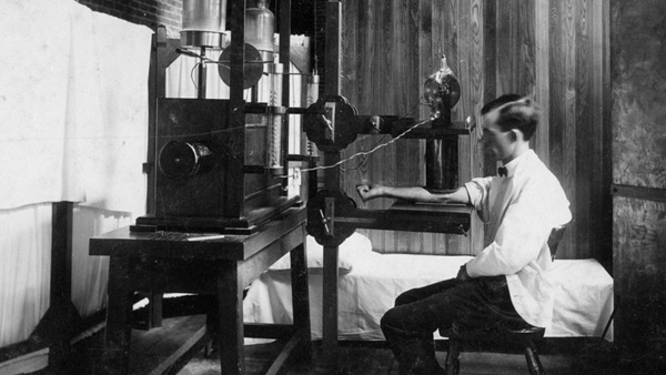 A clinician tests an early X-ray machine in a historical photo A clinician tests an early X-ray machine in a historical photo