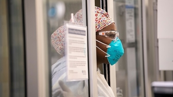 A health care worker looks ahead while wearing a mask and eye protection