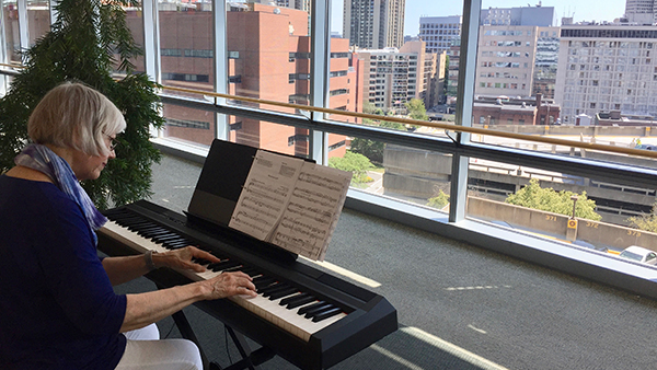 Person playing the piano in the Yawkey building. Person playing the piano in the Yawkey building.